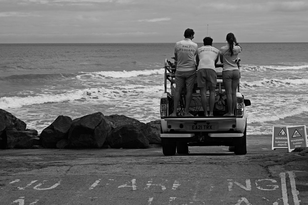 three RNLI coast guards waiting on the back of their truck