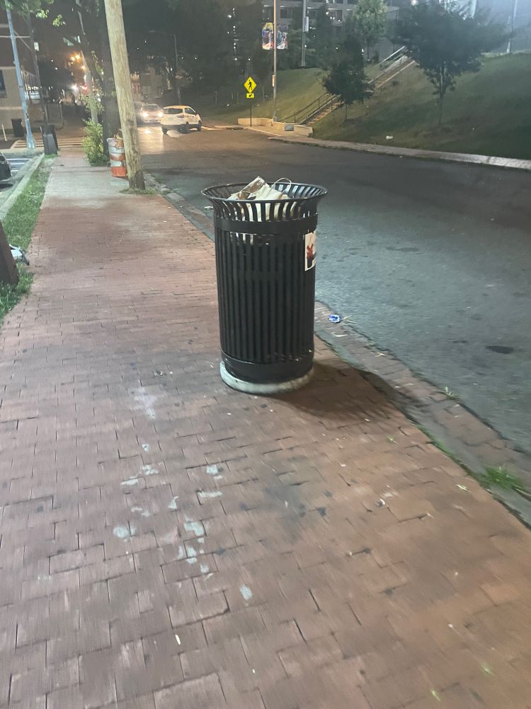 An overflowing public trash can