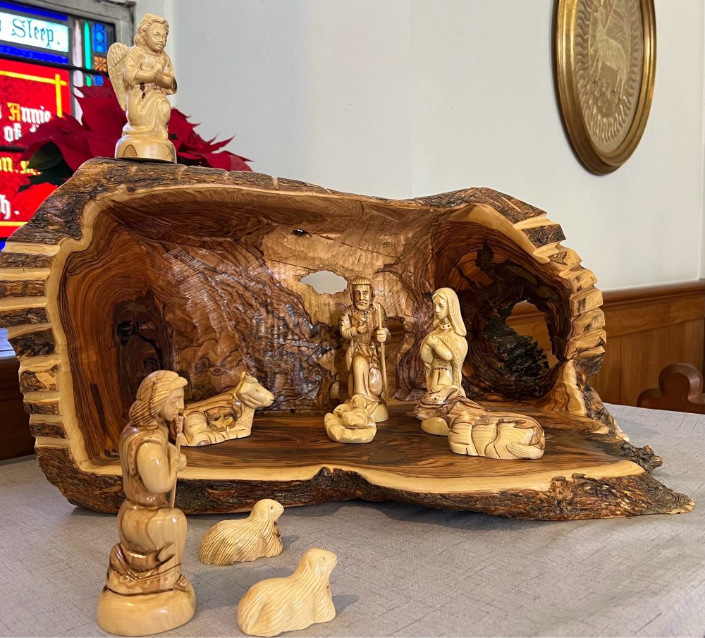 A Nativity scene hand carved from olive wood by Palestinian Christians. The cave is carved out of one large dark piece of wood while the figures are lighter.