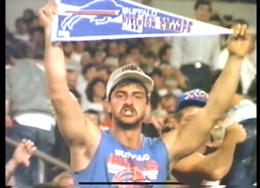 90s bills fan in sleeveless shirt holding a bills division champs pennant 