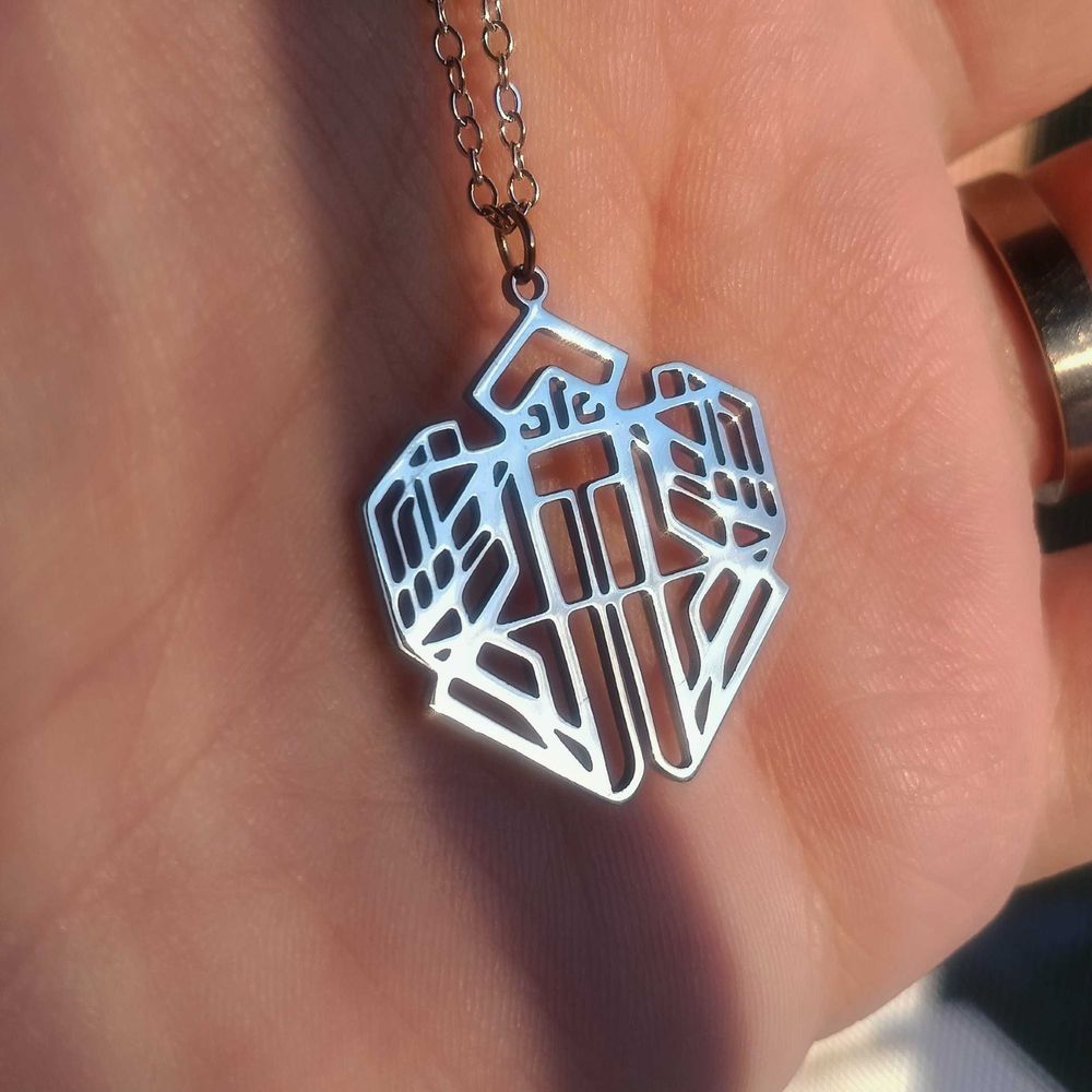 A hand showcasing a necklace that looks like Lune's Necklace from Expedition 33: Clair Obscur
