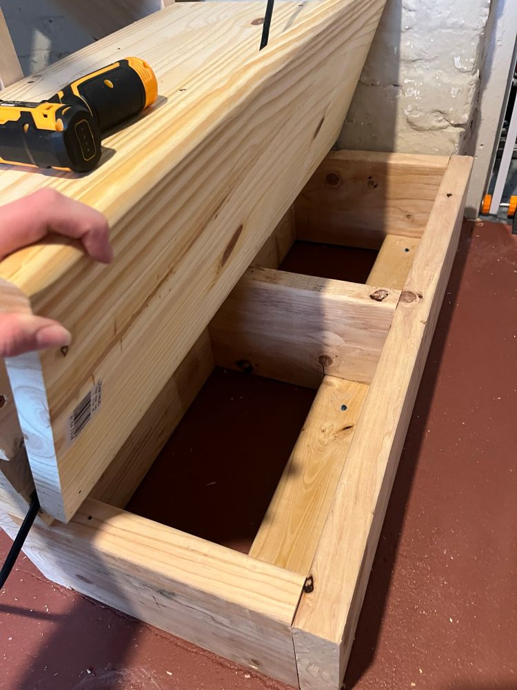 Wooden step at bottom of staircase hinged open to show storage inside 