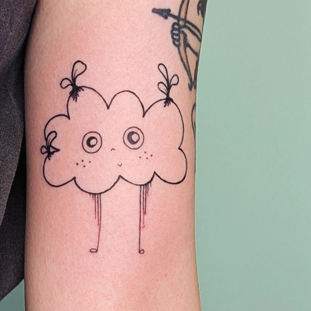 Tattoo of a freckled smiling cloud with rain legs and lil sprouts growing from its head on light skin with a slightly green background 