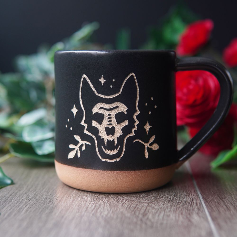The silhouette of a German shepherd dog with its skull filled in, engraved on a black mug. 