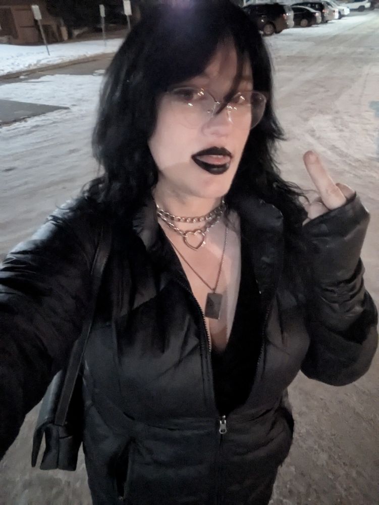 triz with dyed black hair in a  black coat and dress