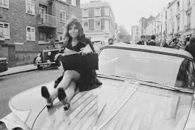 Jane on the bonnet of a painted Buick. The photo is black & white.
