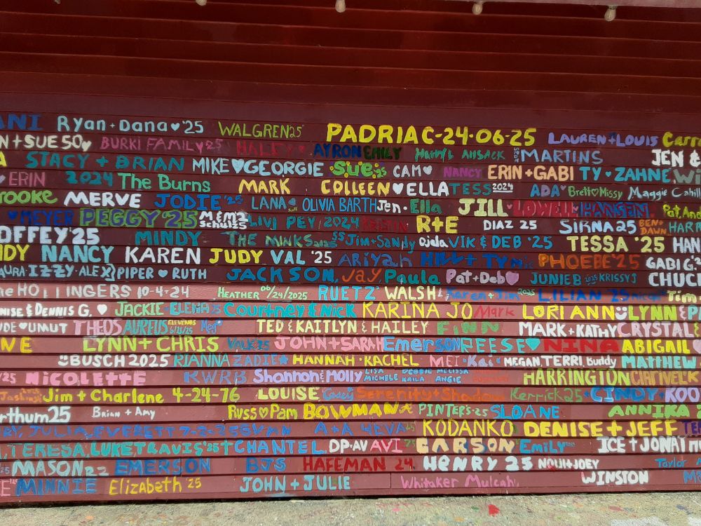 detail of wall with names painted onto it in multiple colors 