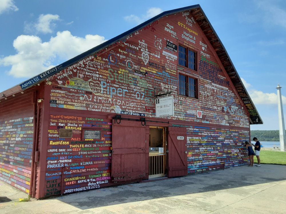 Wooden building with walls covered in names painted onto it.