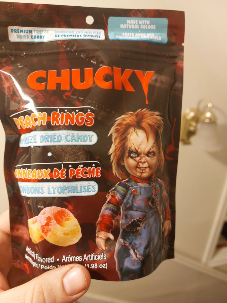 A package of candy with scarred Chucky on the bag. "Chucky Peach Rings freeze dried candy"