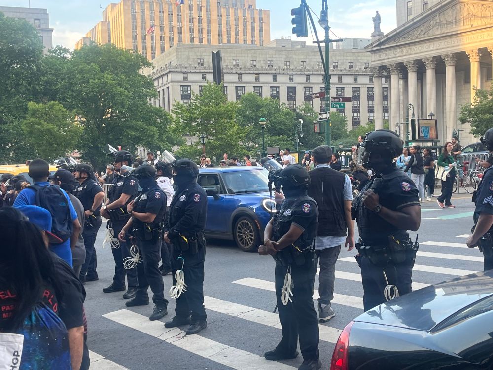 A line of police officers with zip tie cuffs, masks, helmets outside 26 federal plaza in NYC 