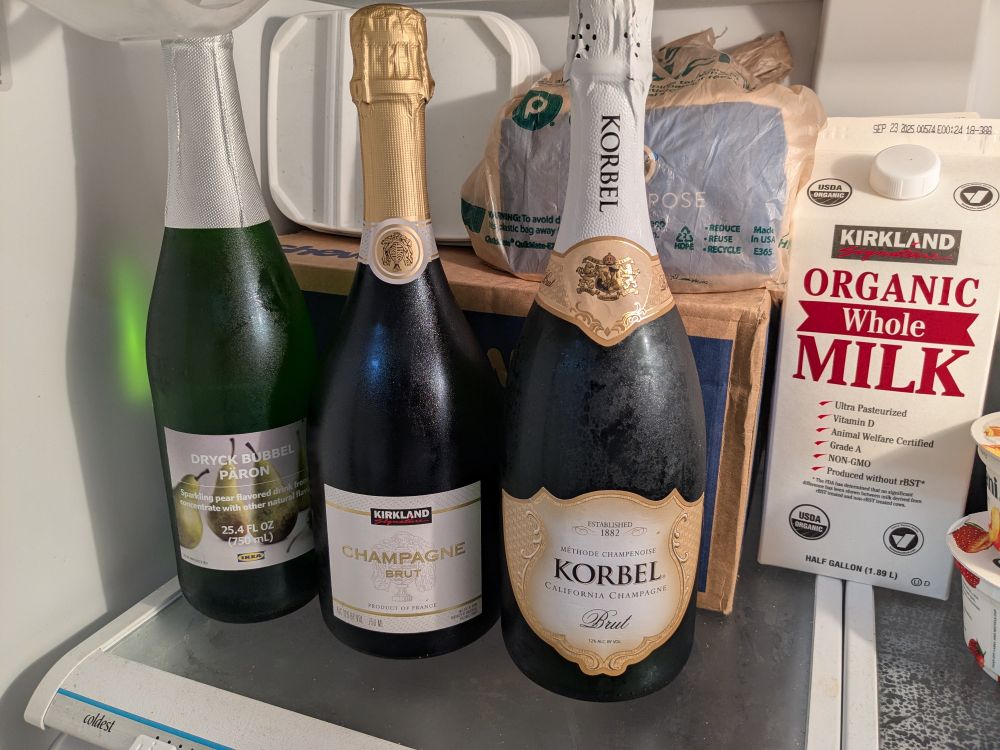 2 bottles of champagne and 1 bottle of sparkling fruit juice in a refrigerator 