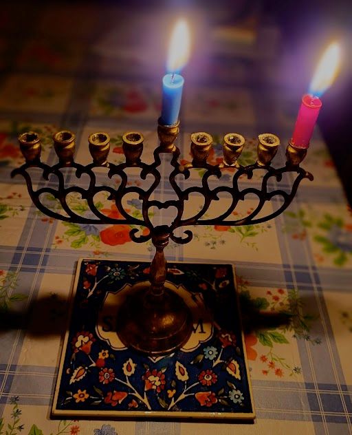 A simple hanukkiah with 2 candles burning down, one blue, one red