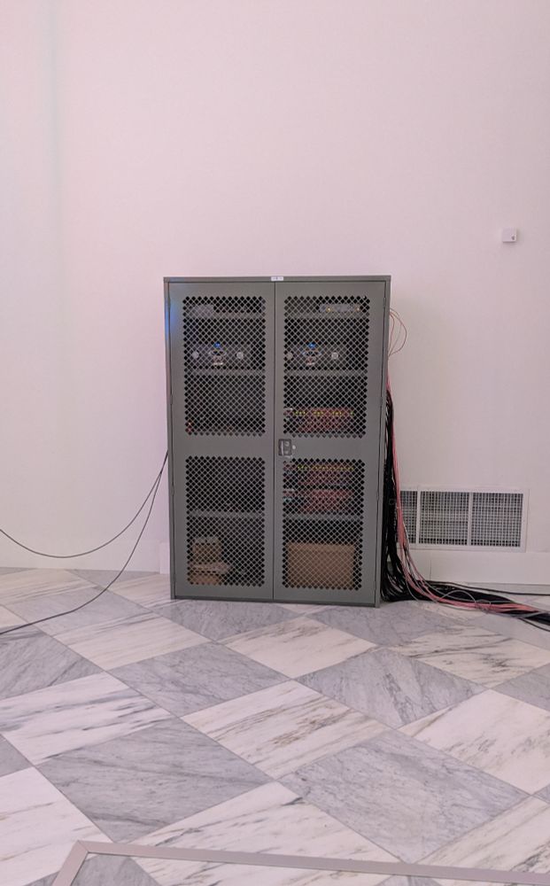 A photo of a cabinet with some of the devices from the back end of 

Nam June Paik, Electronic Superhighway: Continental U.S., Alaska, Hawaii, 1995, fifty-one channel video installation (including one closed-circuit television feed), custom electronics, neon lighting, steel and wood; color, sound, approx. 15 x 40 x 4 ft., Smithsonian American Art Museum, Gift of the artist, 2002.23
