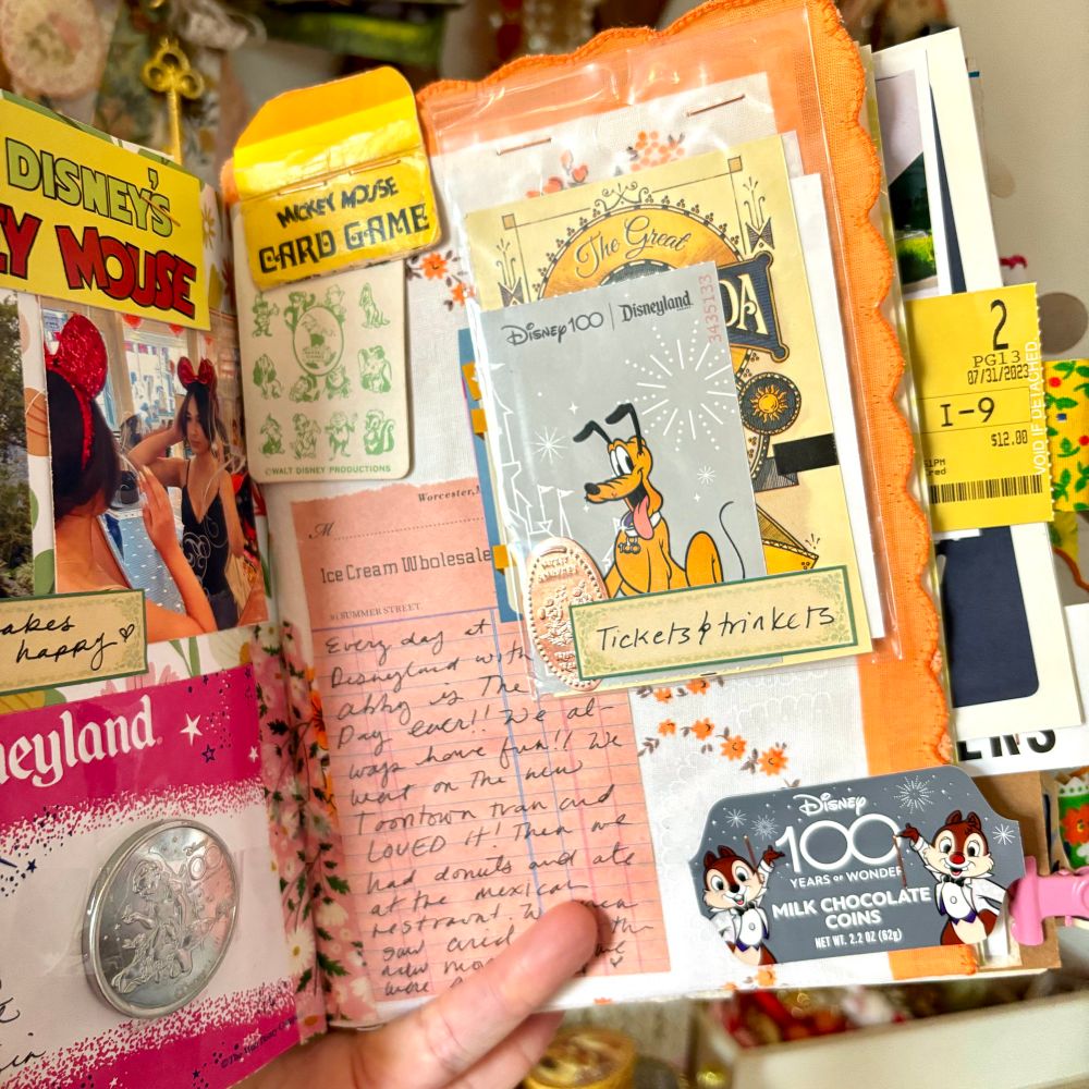 Journal layout with my Disneyland ticket with Pluto on the front. An old plastic bag with a pressed penny and other trinkets. Old packaging from the Disneyland day. My written journaling on a peach piece of paper.