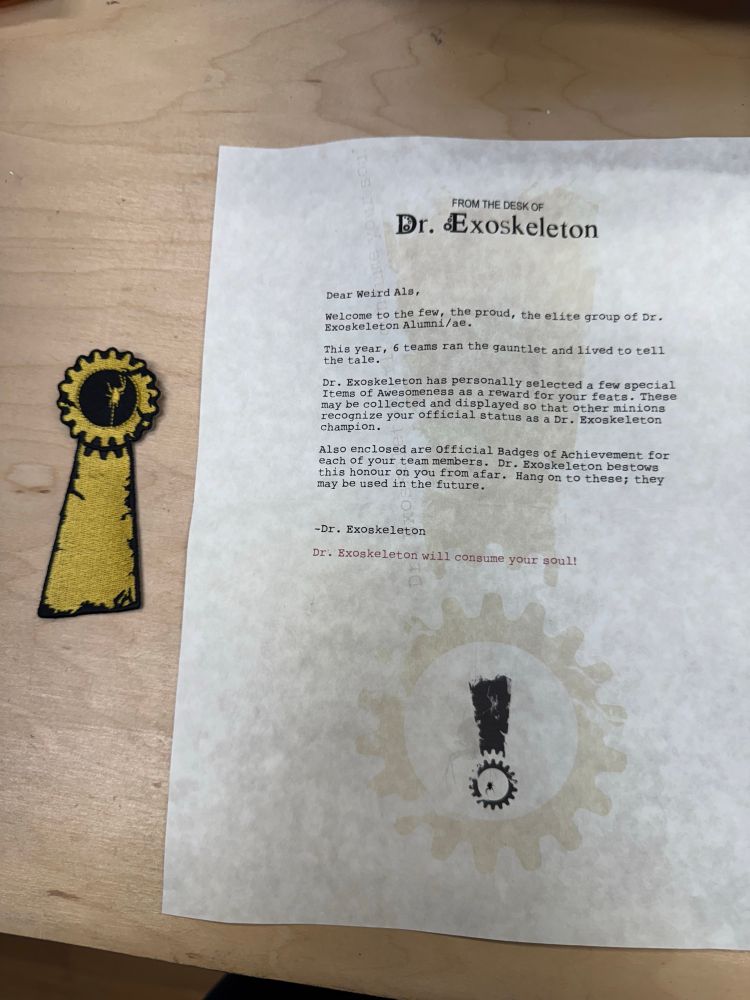 A badge and letter signifying completion of the Dr. Exoskeleton challenge at PAX. The letter says: Dr Exoskeleton Dear Weird Al’s, welcome to the few the proud and the elite group of Dr Exoskeleton Alumni/ae. This year, 6 teams ran the gauntlet and loved to tell the tale. Dr. Exoskeleton has personally selected a few special items of awesomeness as a reward for your feats. These may be collected and displayed so that other minions recognize your official status as a Dr. Exoskeleton champion. Also enclosed are official badges of achievement for each of your team members. Dr Exoskeleton bestows this honor on you from afar. Hang on to these, they may be used in the future. -Dr. Exoskeleton

In red ink below it says: Dr Exoskeleton will consume your soul!