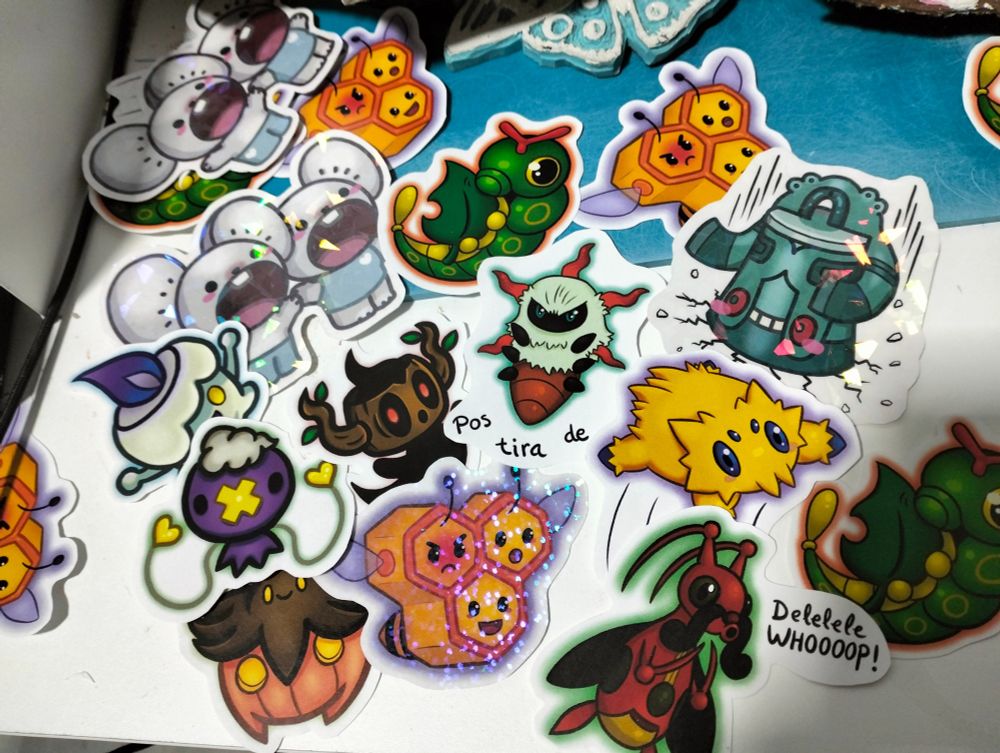 Enganxines colorides representant diverses criatures del videojoc Pokémon escampades sobre una taula.