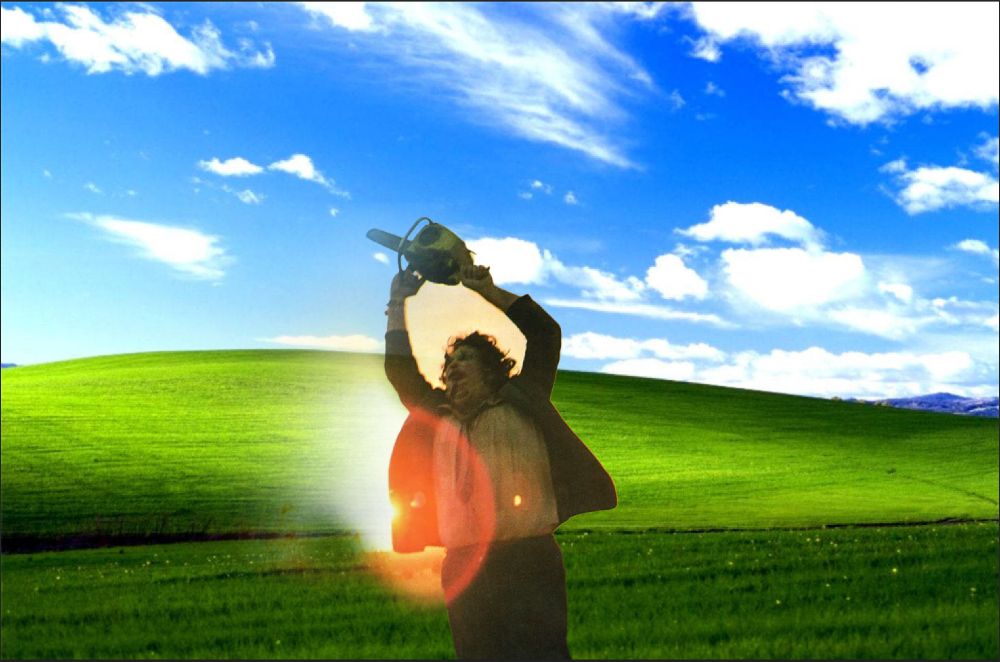 A badly photoshopped image of Leatherface, swinginging his chainsaw in the final shot of Texas Chain-Saw Massacre, superimposed over the rolling grass and blue sky Windows 95 backdrop. 