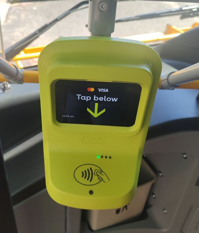 a tap-and-go card reader on a wangaratta bus, which is mainly lime-green but features a dark screen with an arrow pointing below, indicating where one should tap their card