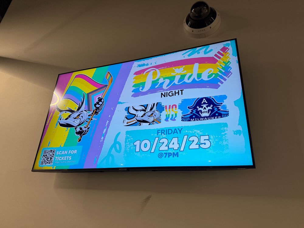 A TV with the event sign for Pride Night at the SJ Barracuda v. Milwaukee Admirals who were very mean to my AHL team for literally no reason.