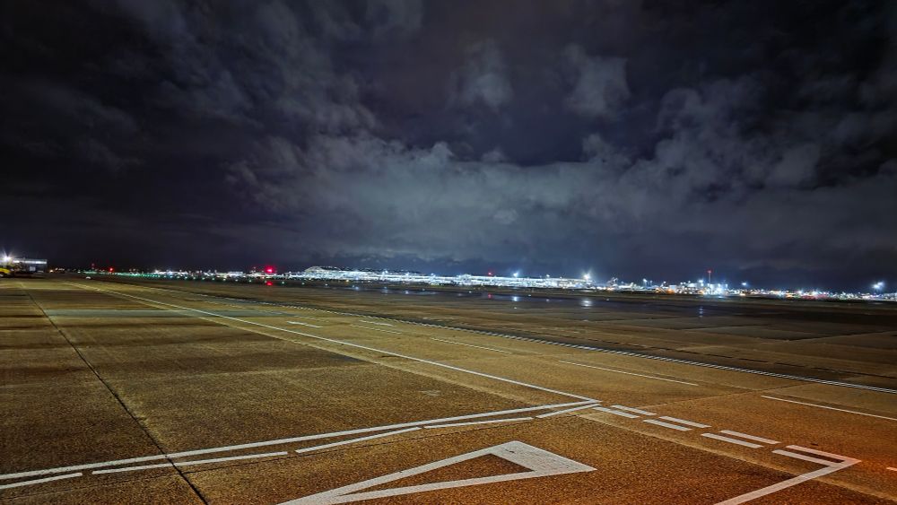 LHR after dark, picture of a runway with a terminal building in the background. 