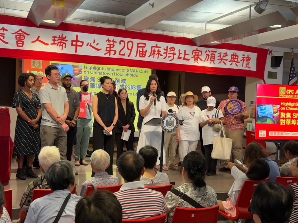 a photo of a press conference held at the Chinese-American Planning Council’s Older Adult Center in NYC Chinatown on the impact of federal funding cuts to SNAP. on stage are NY Congressman Dan Goldman, NY Assemblymember Grace Lee, and 1199 delegate Yan N. Looi wearing a purple 1199 homecare hat. 