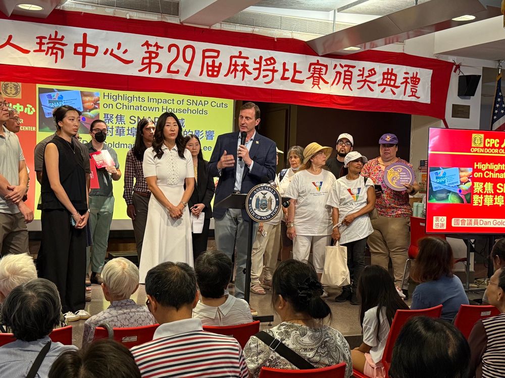 a photo of a press conference held at the Chinese-American Planning Council’s Older Adult Center in NYC Chinatown on the impact of federal funding cuts to SNAP. on stage are NY Congressman Dan Goldman, NY Assemblymember Grace Lee, and 1199 delegate Yan N. Looi wearing a purple 1199 homecare hat. 
