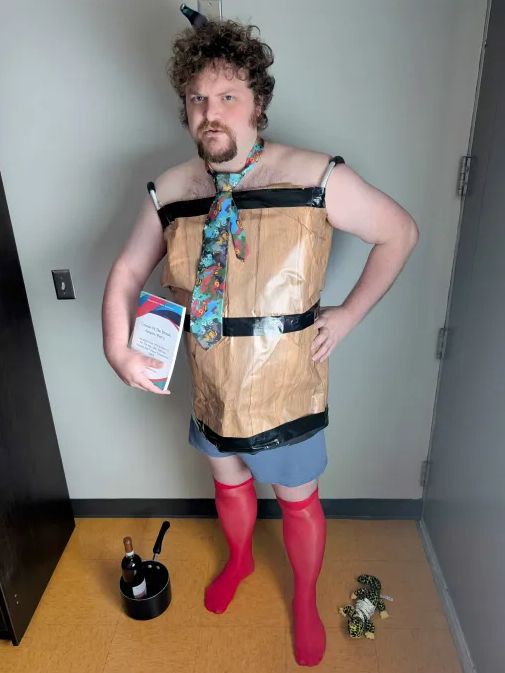 A person wearing real-life appropximations of the outfit that would get you the maximum scandal in Fallen London: red stockings, a barrel on a pair of braces, and a hideous necktie.