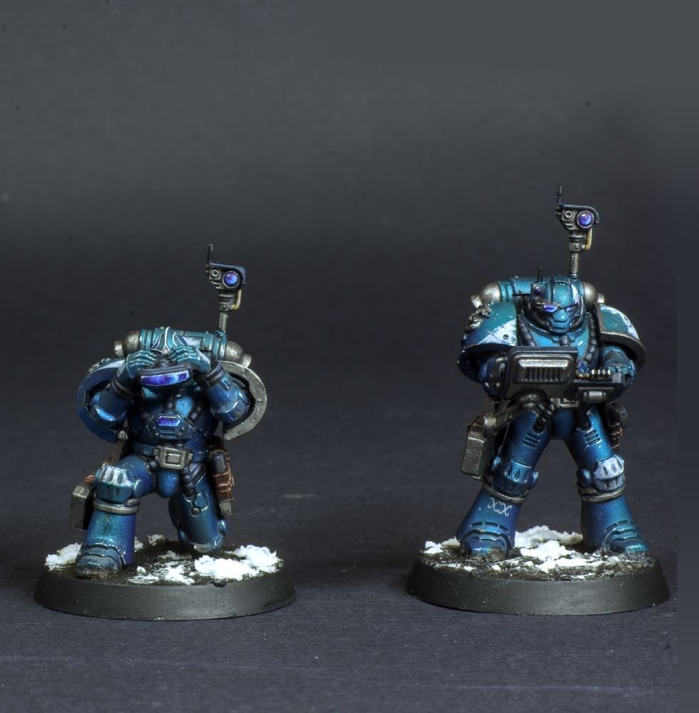 Photo de deux figurines space marine de warhammer 30000 l'hérésie d'horus. Iel sont de l'alpha légion, couleur bleu métallique avec des détails blancs. Elles ont de nombreux équipements d'analyse. 