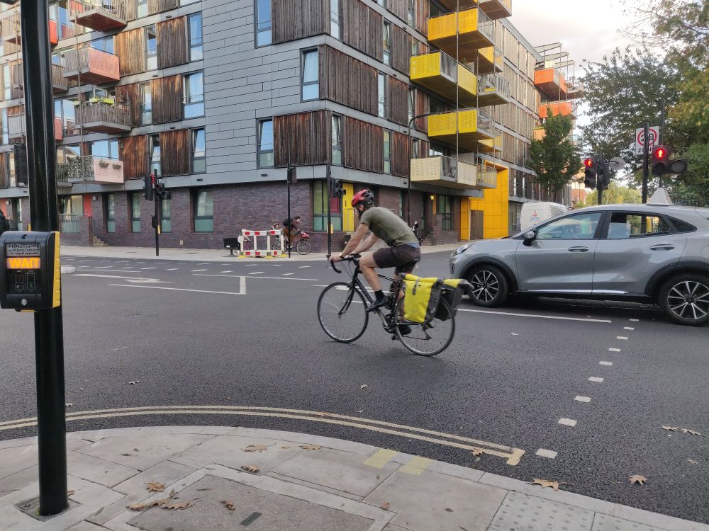 Person on a road bike with yellows panniers cycling in prime position through the Queensbridge Road junction with Whiston Road