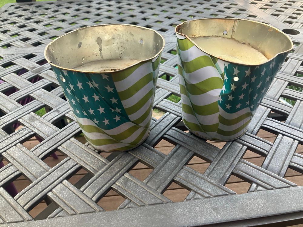 2 citronella candle holders with American flag design on the outside. They are banged up and the colors are faded 