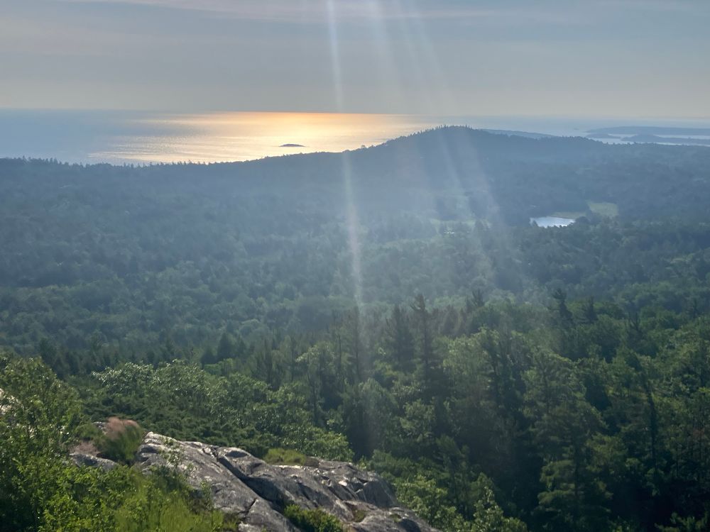 Scenic pictures from the top of a peak. Lake Superior is glowing the distance and there is a pretty forest in the foreground 