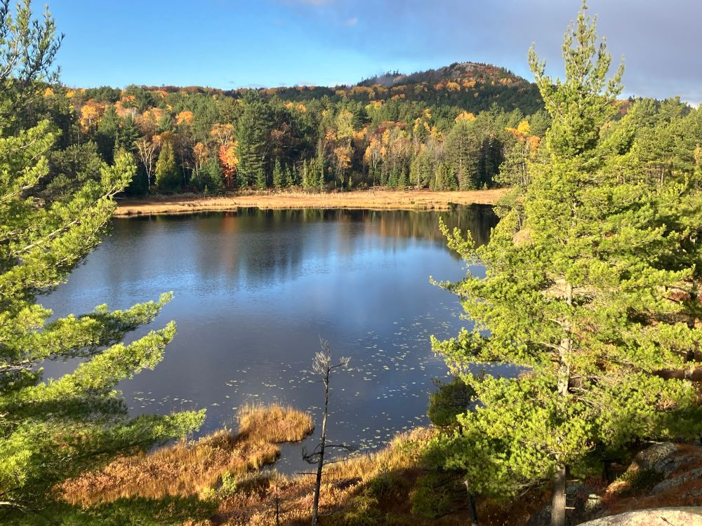 A lake with a colorful hill in the background 