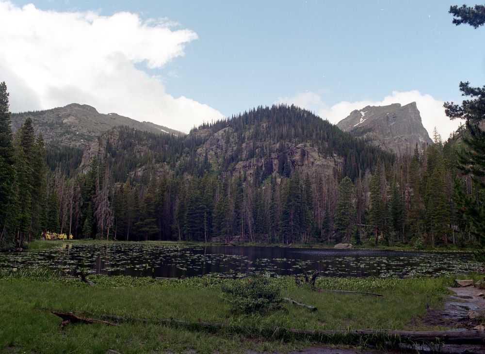 Rocky Mountain landscape with a group in ponchos tucked away on the left border