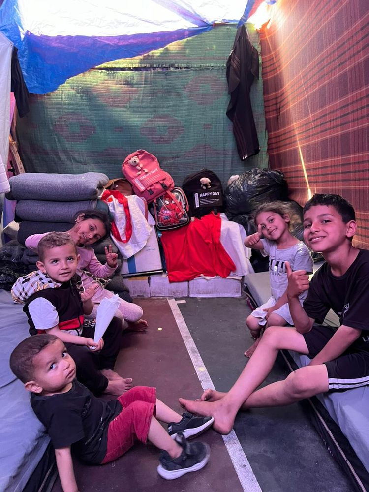 Five little children in a tent, making peace signs and giving thumbs up