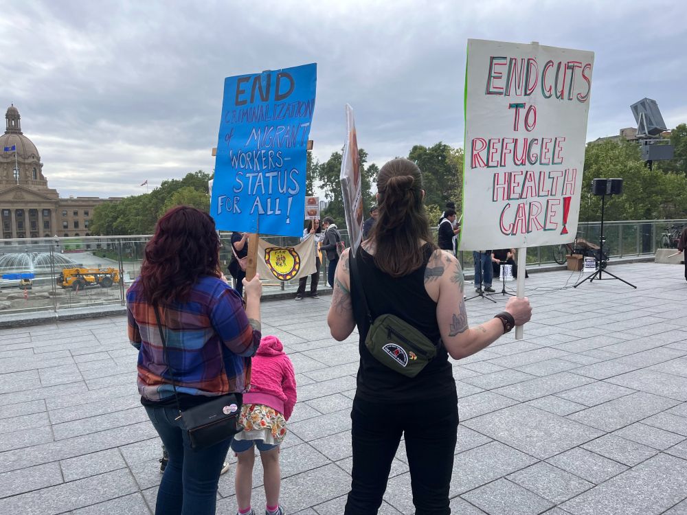 People holding signs at a migrant rights rally.