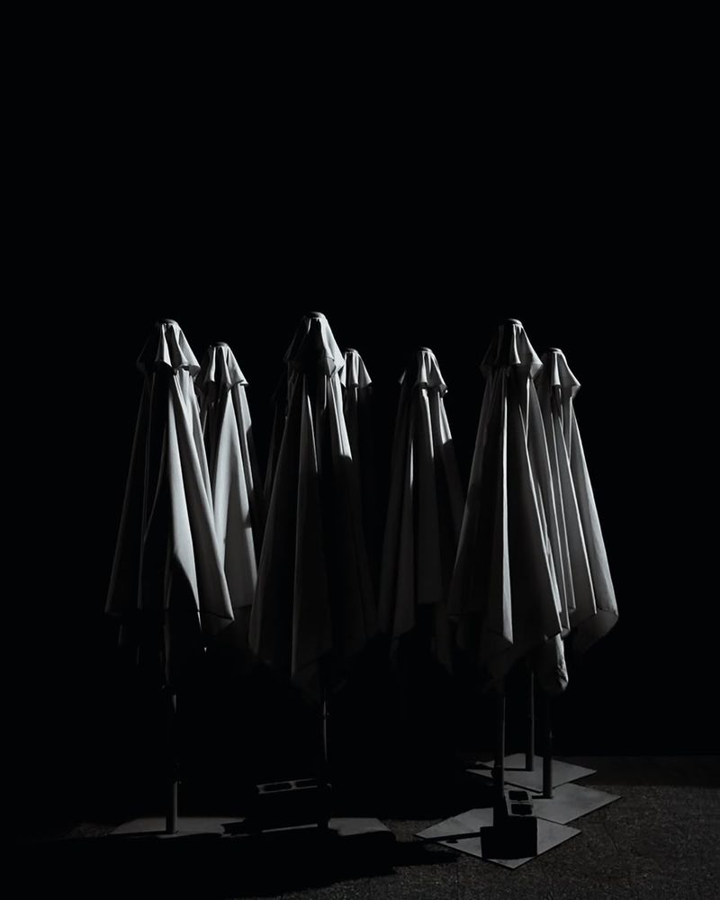 Sombrillas cerradas de bar por la noche que parecen nazarenos