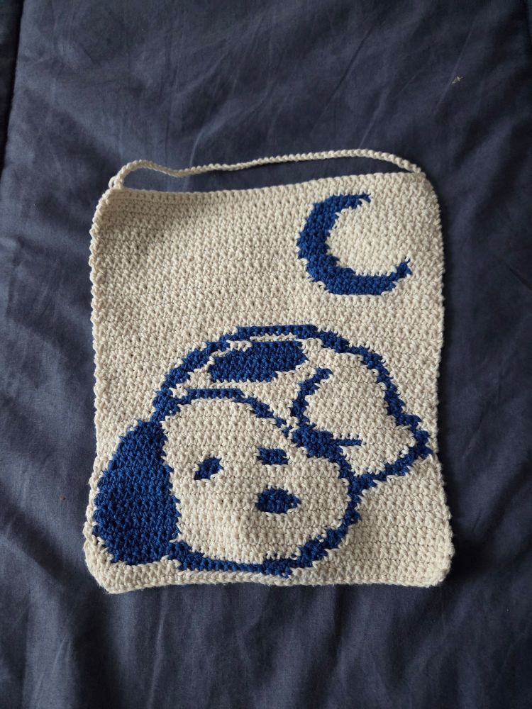 tapeçaria de crochet branca com o snoopy deitadinhk em azul 