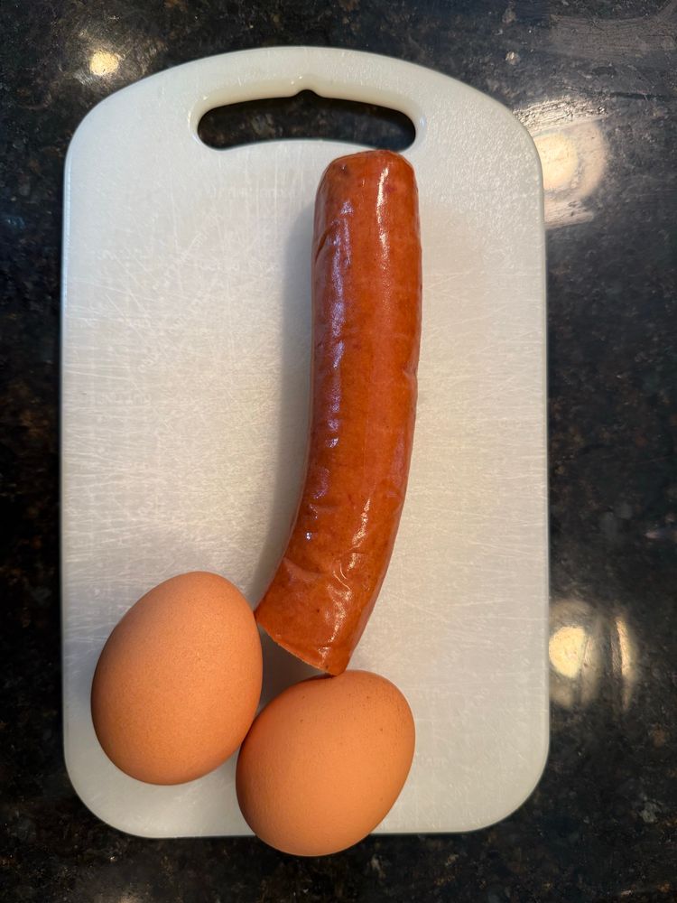 Sausage and eggs placed on a cutting board in the form of a dick and balls 