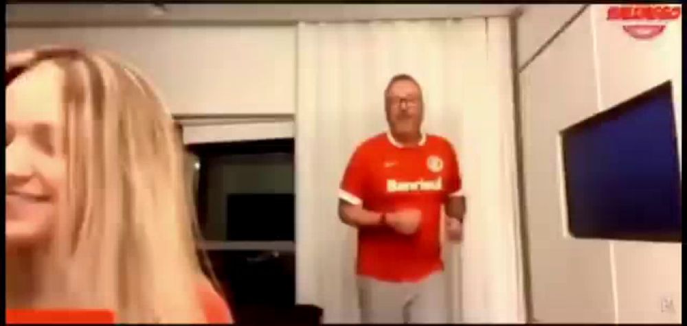 a man in a red shirt is dancing in a living room with a woman .