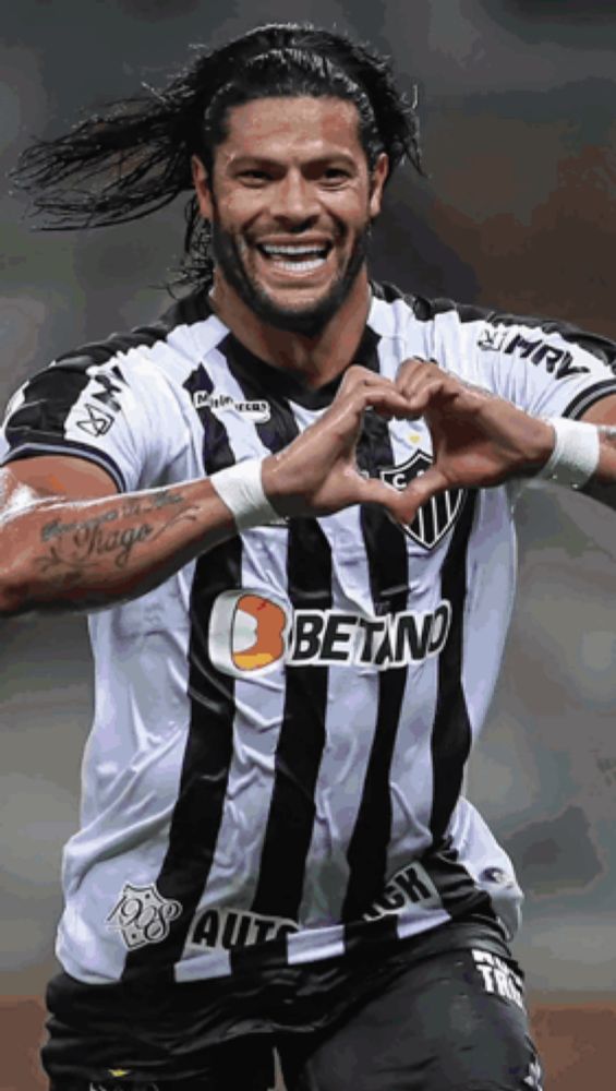 a soccer player wearing a betano jersey making a heart shape with his hands