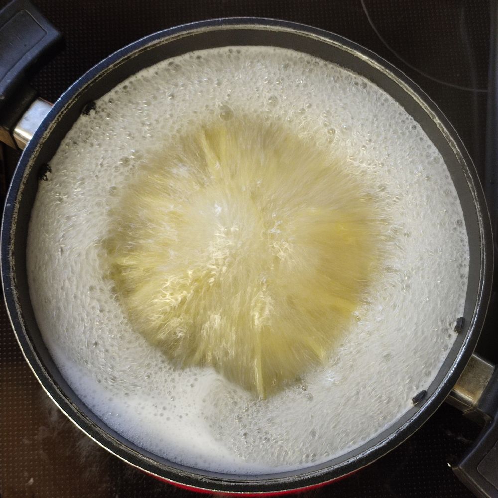 鍋でパスタを茹でている様子。熱湯の対流により麺が躍動している。