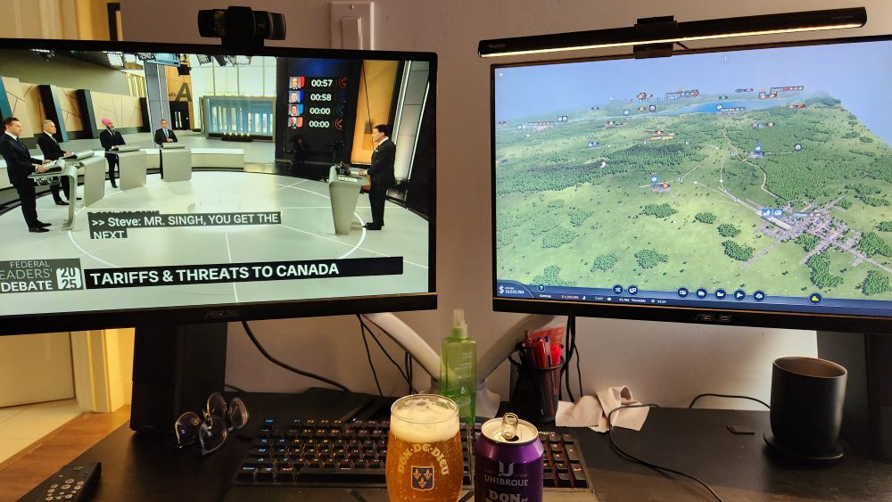 Picture of my computer set up, with the debate on one monitor and the game Transport Fever 2 on the other