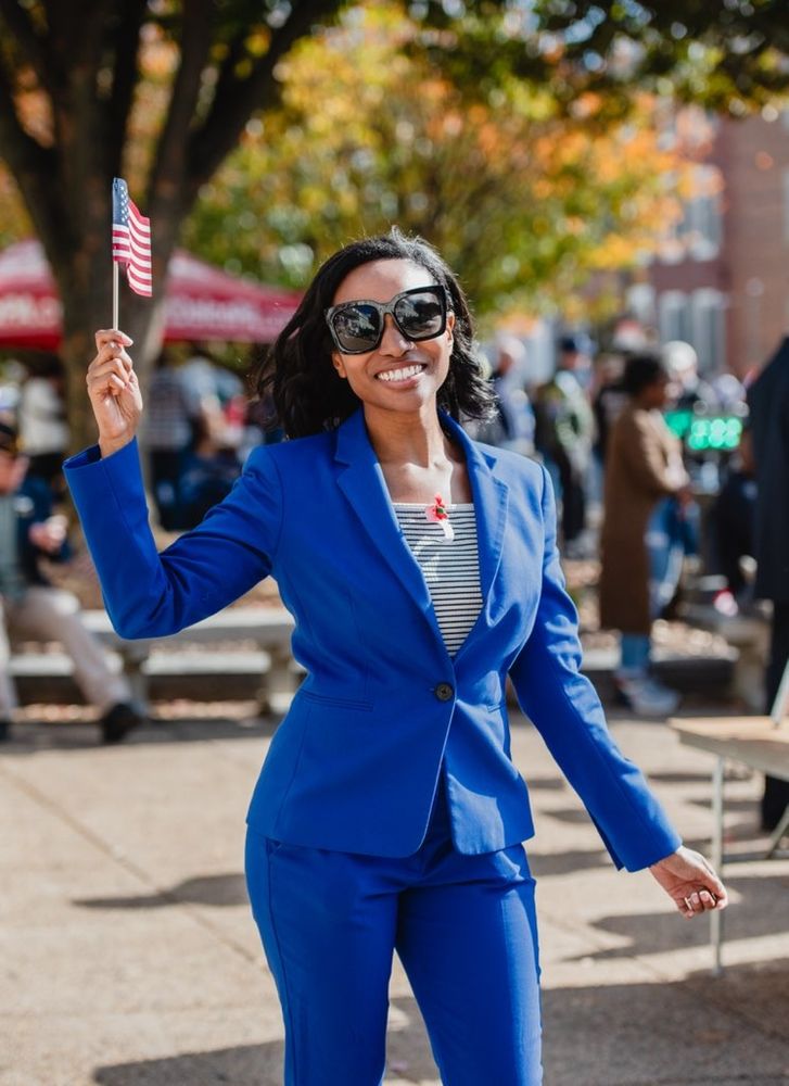 OP smiling in a photo wearing a blue suit holding an American flag.