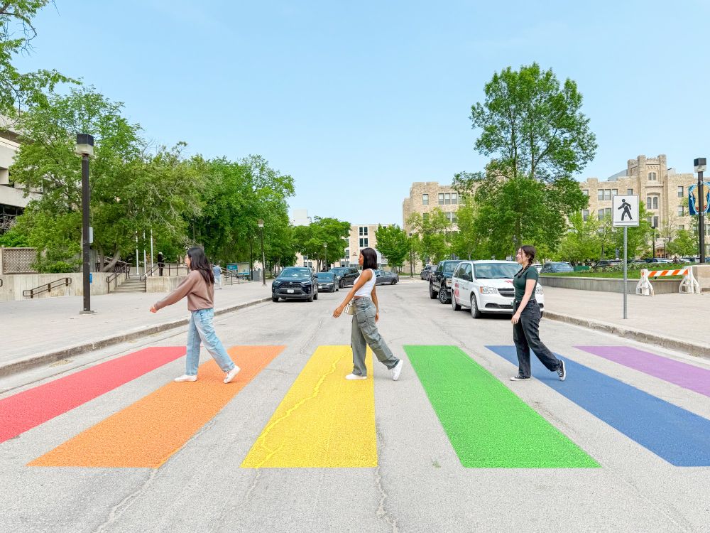 Three females walking on a rainbow coloured crosswalk