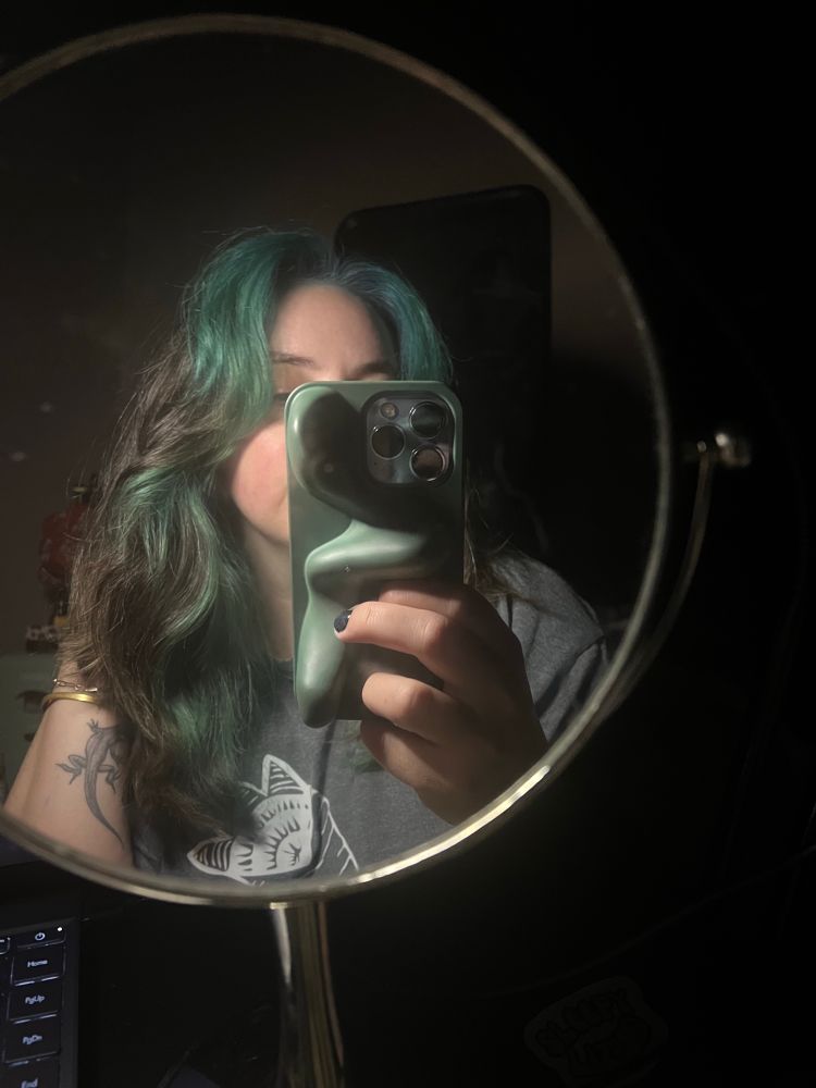 clue mirror selfie showing her hair which she’s dyed. the front which was peach is now a deep blue green. it’s giving sea witch 