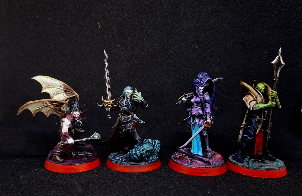 Four painted miniatures of vampires standing in line.