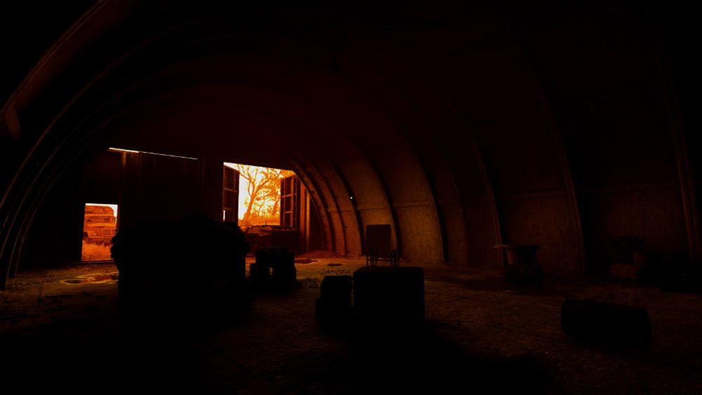 A screenshot from STALKER 2 videogame. An eerie red sky dimly illuminates a half-dome concrete tunnel.