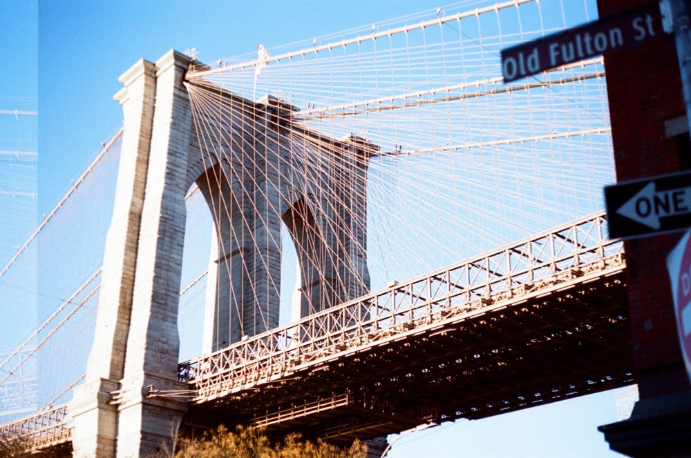 Close up of the Brooklyn bridge, from the Brooklyn side. Some street signs are visible in the immediate foreground, accidental double exposure for one small strip on the left edge