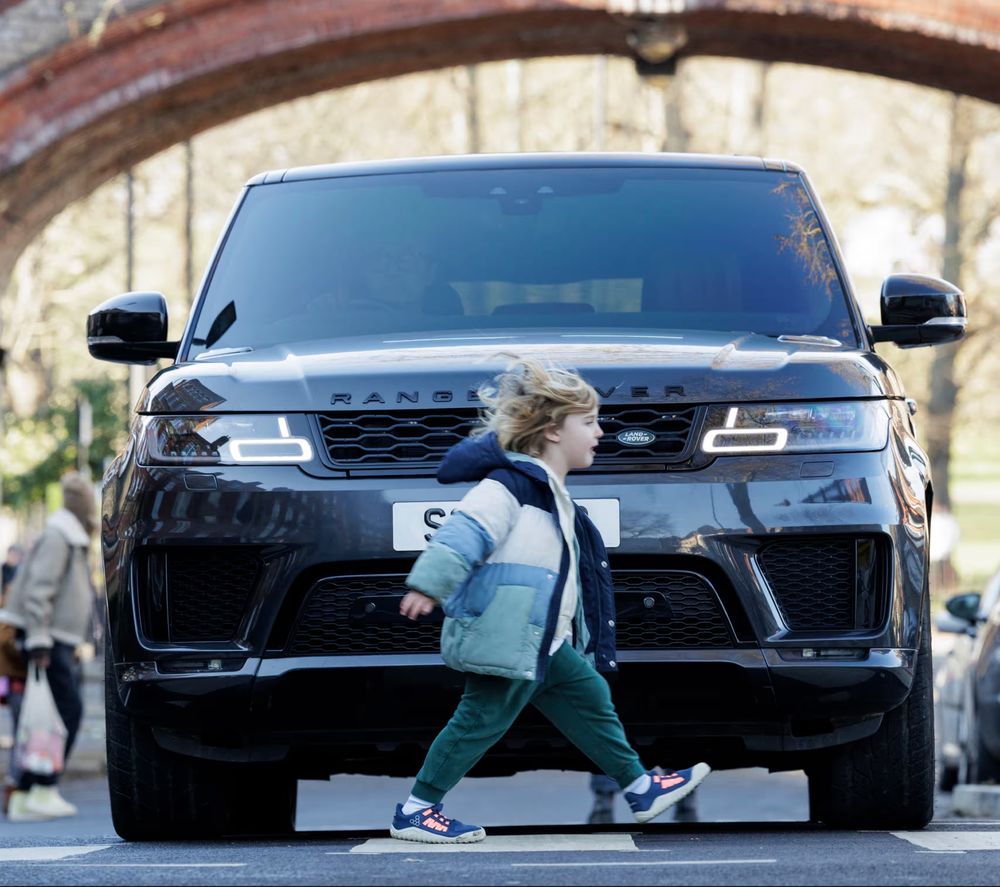 Foto eines Volkschulkindes vor einem Range Rover
