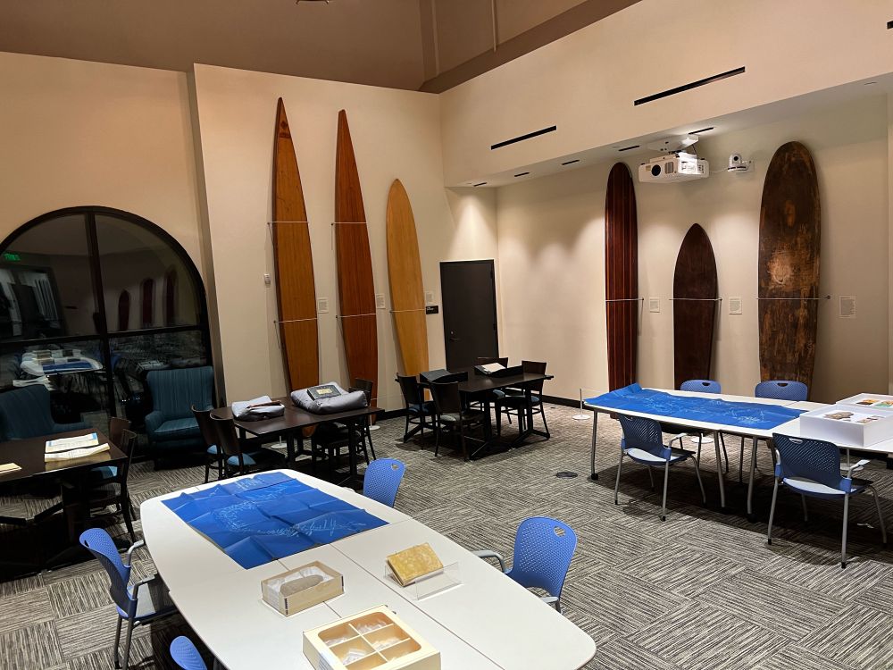 Special Collections instruction session tables laden with materials focusing on land use throughout Malibu history. Historic surf and paddle boards line the walls.